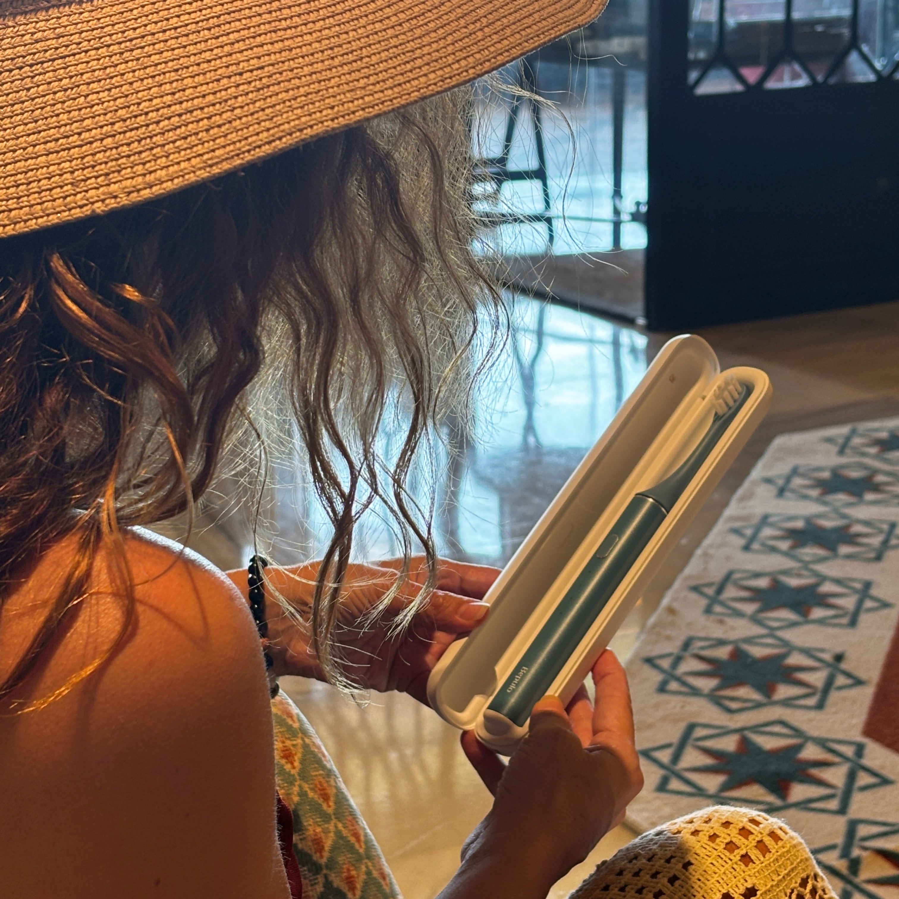A person holding a Bepulo Electric Toothbrush in a white UVC travel case