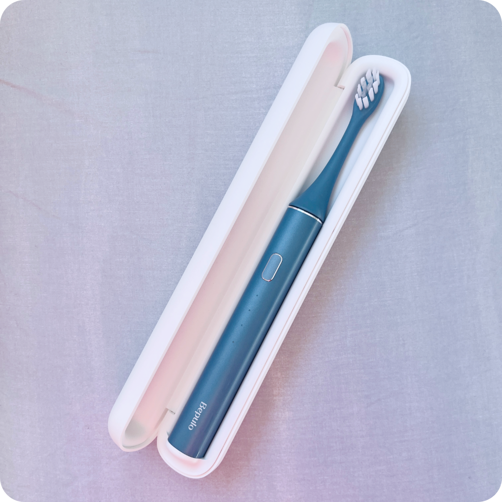 Two electric toothbrushes, one blue and one pink, in a white case on a light gray background.