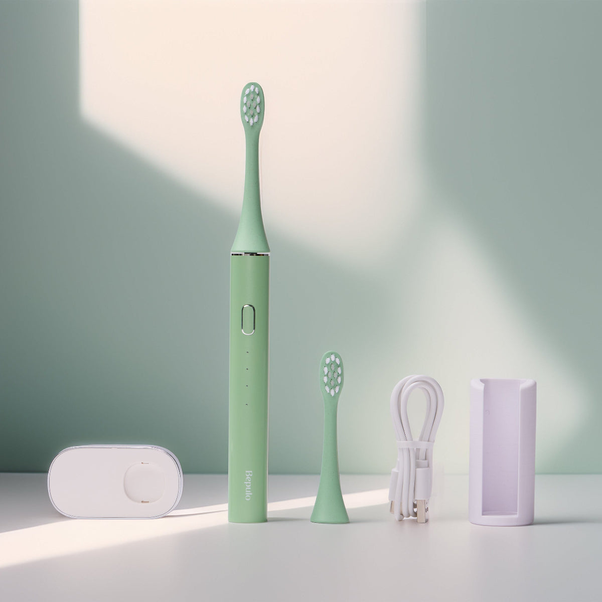 Pistachio green Bepulo Next sonic electric toothbrush standing with a wall holder, magnetic charging base, and USB-C cable. #colour_pistachio green
