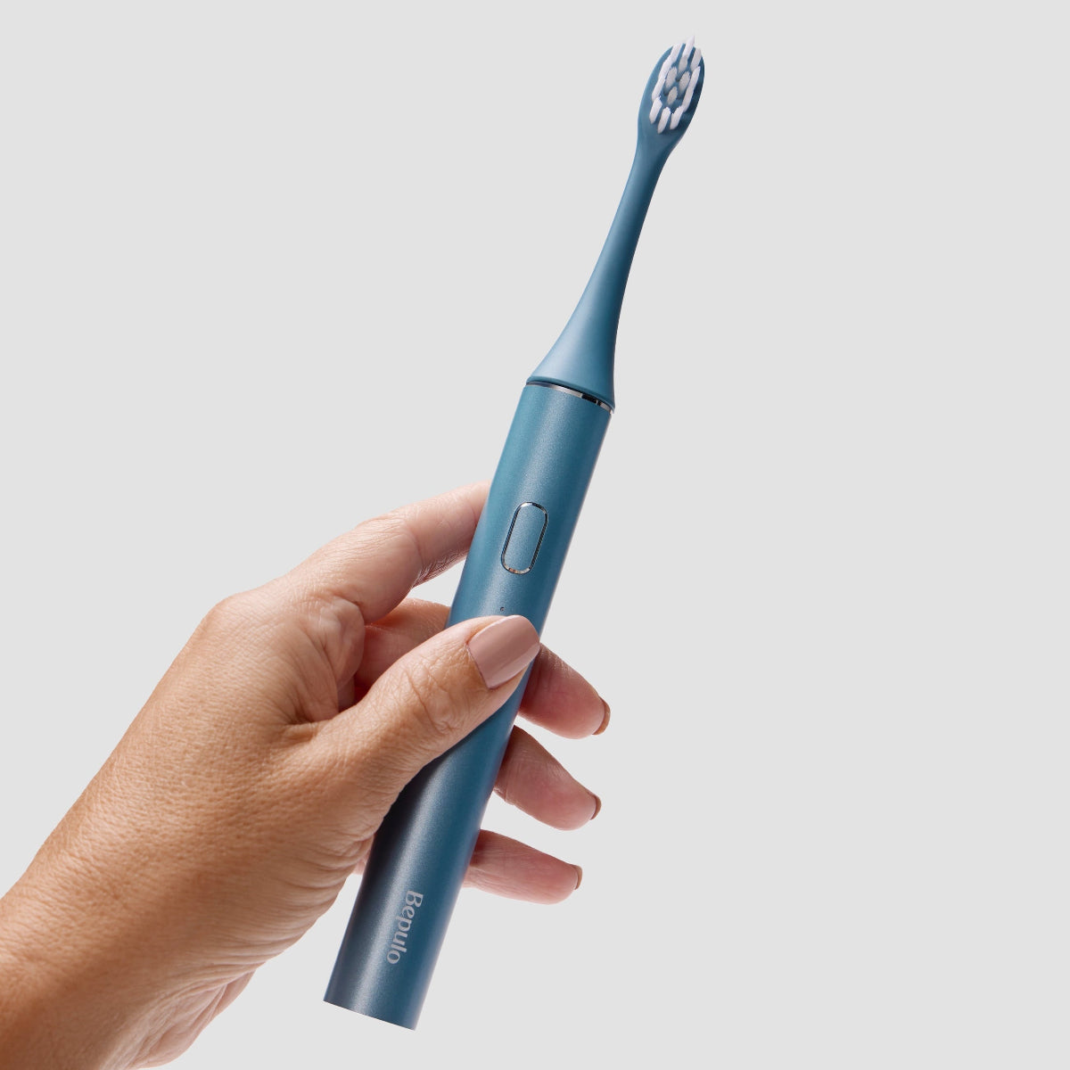 Hand holding a sapphire blue Bepulo Next sonic electric toothbrush with an alloy handle.. #colour_sapphire blue