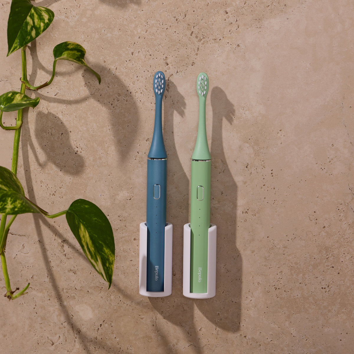 Two Bepulo Next sonic electric toothbrushes mounted on white bathroom wall holders. #colour_sapphire blue and pistachio green
