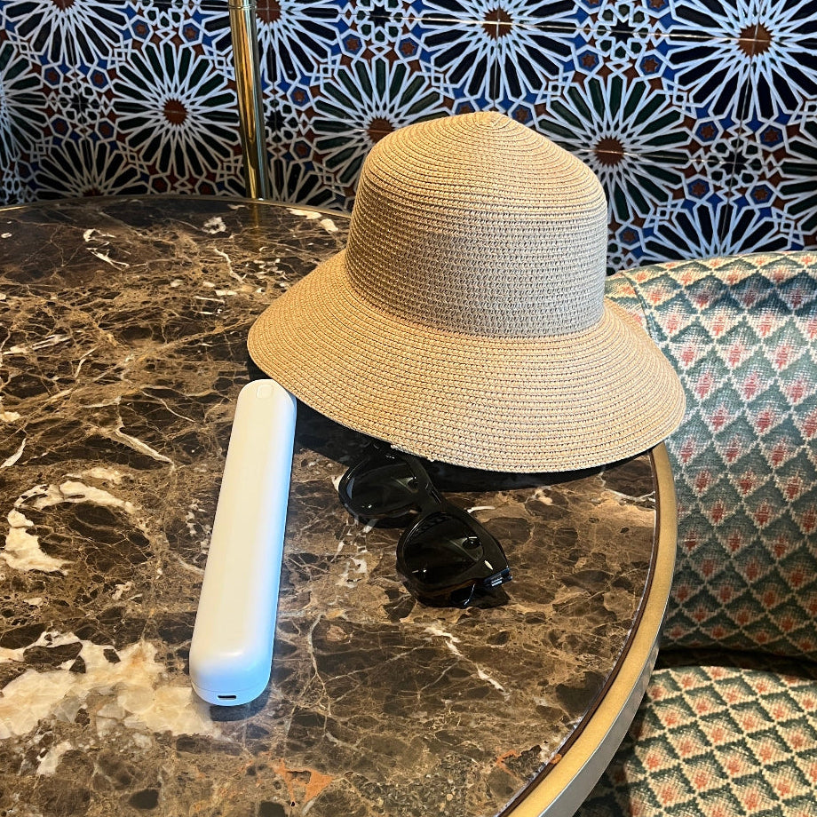 White Bepulo Next electric toothbrush travel case resting on a marble table with sunglasses.